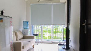 A room with a sofa, a water dispenser, a large window with a view, and a door. - Comfy and Best View 2BR at Serpong Greenview Apartment (South Tangerang)