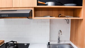 Una cocina moderna con estufa a gas, pileta de acero inoxidable, armarios de madera y extractor de aire negro.