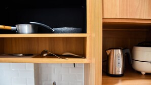 Una cocina con estantes de madera, un hervidor y una cocedora de arroz.