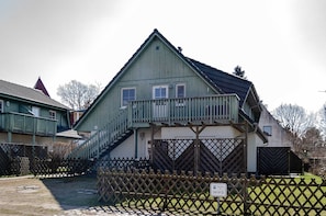 A two-story building with a balcony, a staircase, and a fenced yard.