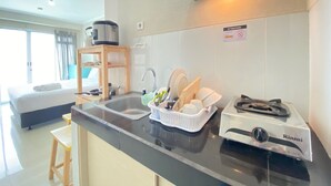 Cozinha compacta com pia, fogão e prateleira de madeira.