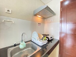 Una cocina con un lavamanos, grifo y un escurreplatos.