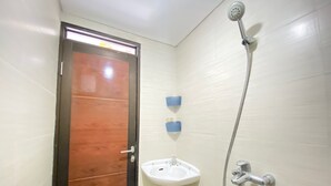 Um banheiro pequeno com porta de madeira, pia branca e chuveiro.
