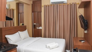 Quarto de hotel com uma cama, escrivaninha, televisão e ar condicionado.