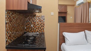 Uma cozinha compacta com fogão a gás, pia e painel de azulejos.