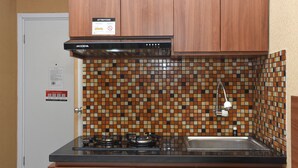 Uma cozinha com bancada preta, fogão, pia e painel de azulejos.