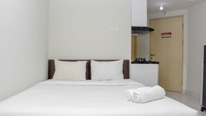 Camera d'albergo con un letto, angolo cottura e una porta con cartello di sicurezza antincendio.