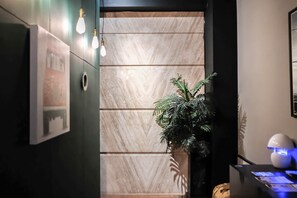 A hallway with a modern design, featuring a wall with a herringbone pattern and a potted plant. - Huzi Room (Tainan)