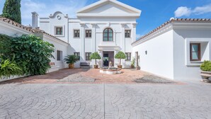 Un bâtiment blanc doté d’une cour intérieure, d’une fontaine et de plantes en pot.