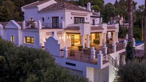 Une maison à plusieurs étages dotée d’un balcon, d’une terrasse couverte et d’un espace piscine.