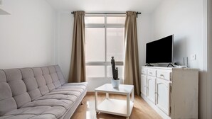 A living room with a sofa, a coffee table, a cabinet, and a television. - Vacation Apartment "Playa Morro Jable 1c" near the Beach with Wi-Fi (Morro Jable)