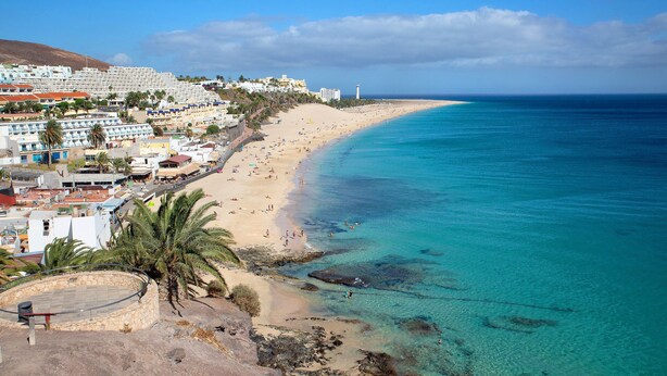 A coastal town with a beach, buildings, and a lighthouse. - Vacation Apartment "Playa Morro Jable 1c" near the Beach with Wi-Fi (Morro Jable)