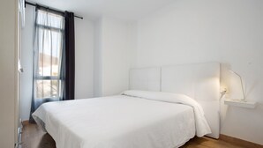 A bedroom with a bed, a nightstand, a window with curtains, and a wall-mounted light. - Vacation Apartment "Playa Morro Jable 1c" near the Beach with Wi-Fi (Morro Jable)