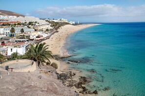A coastal town with a beach, clear blue waters, and buildings along the shore.