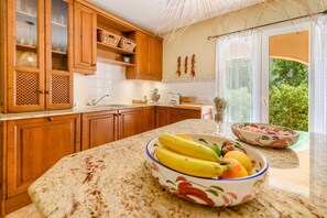 A kitchen with wooden cabinets, a granite countertop, and a bowl of fruit.
