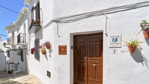 A white building with a brown door, potted plants, and a sign indicating 'Casa Rural.' - Cottage "Casa Loli" with Mountain View, Private Pool & Terrace (Frigiliana)