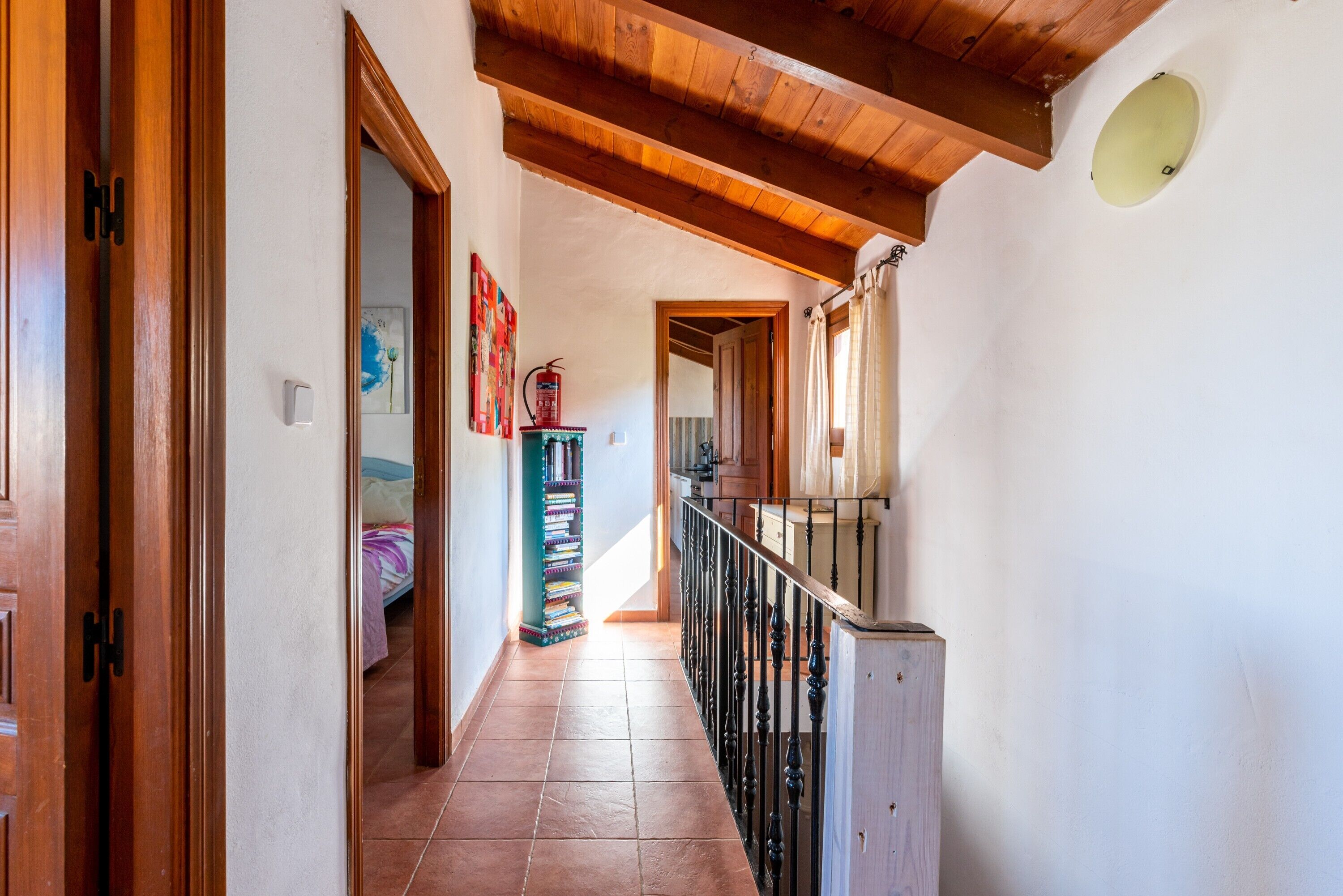 A hallway with wooden doors, a staircase, and a tiled floor.