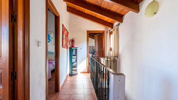 A hallway with wooden doors, a staircase, and a tiled floor.