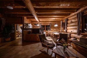 A log cabin interior with a dining area, kitchen, and seating space.