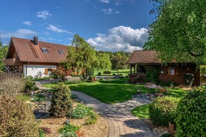 A house with a garden, a patio, and a small wooden structure.