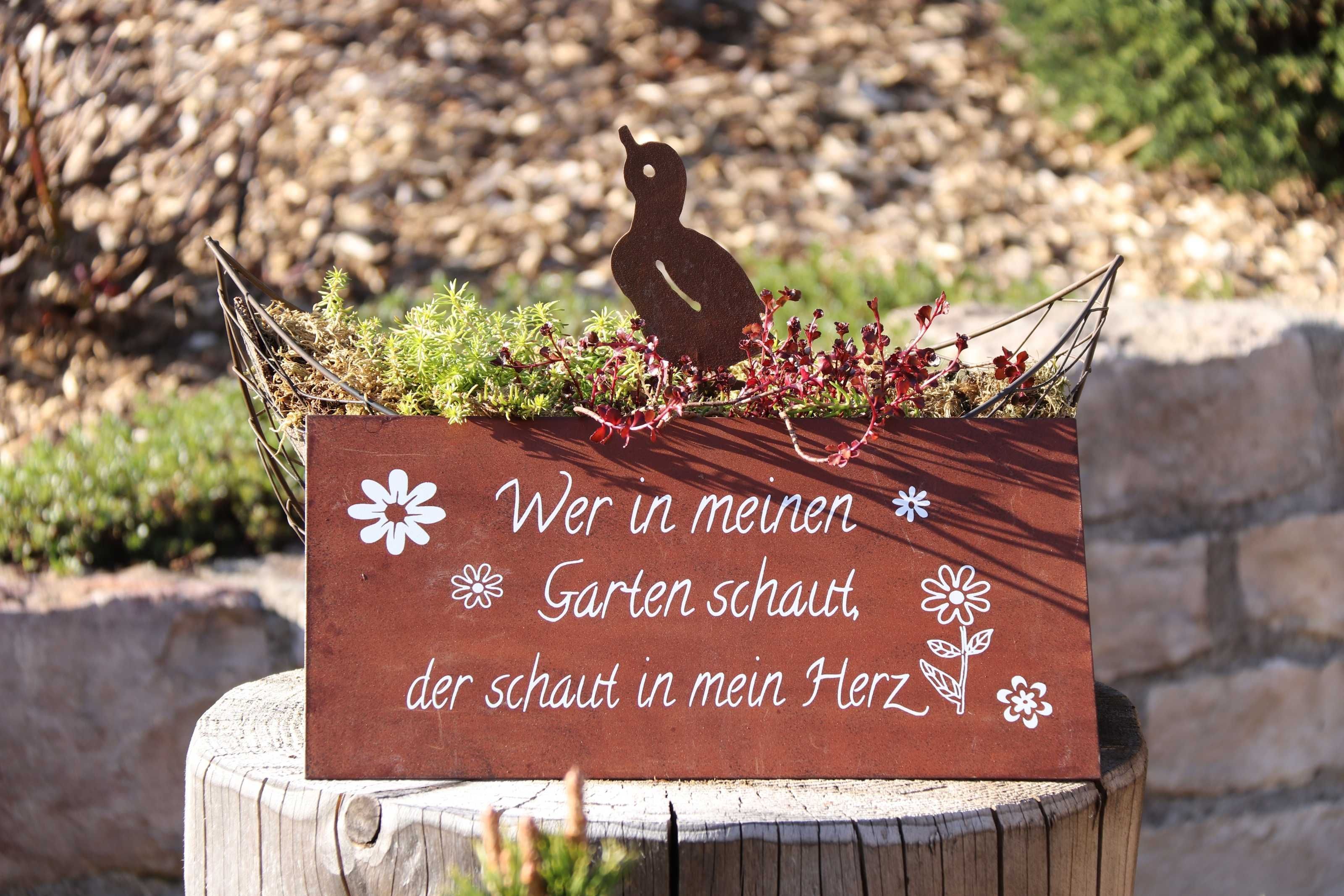 Uma placa de madeira com silhueta de urso e texto, em um jardim.