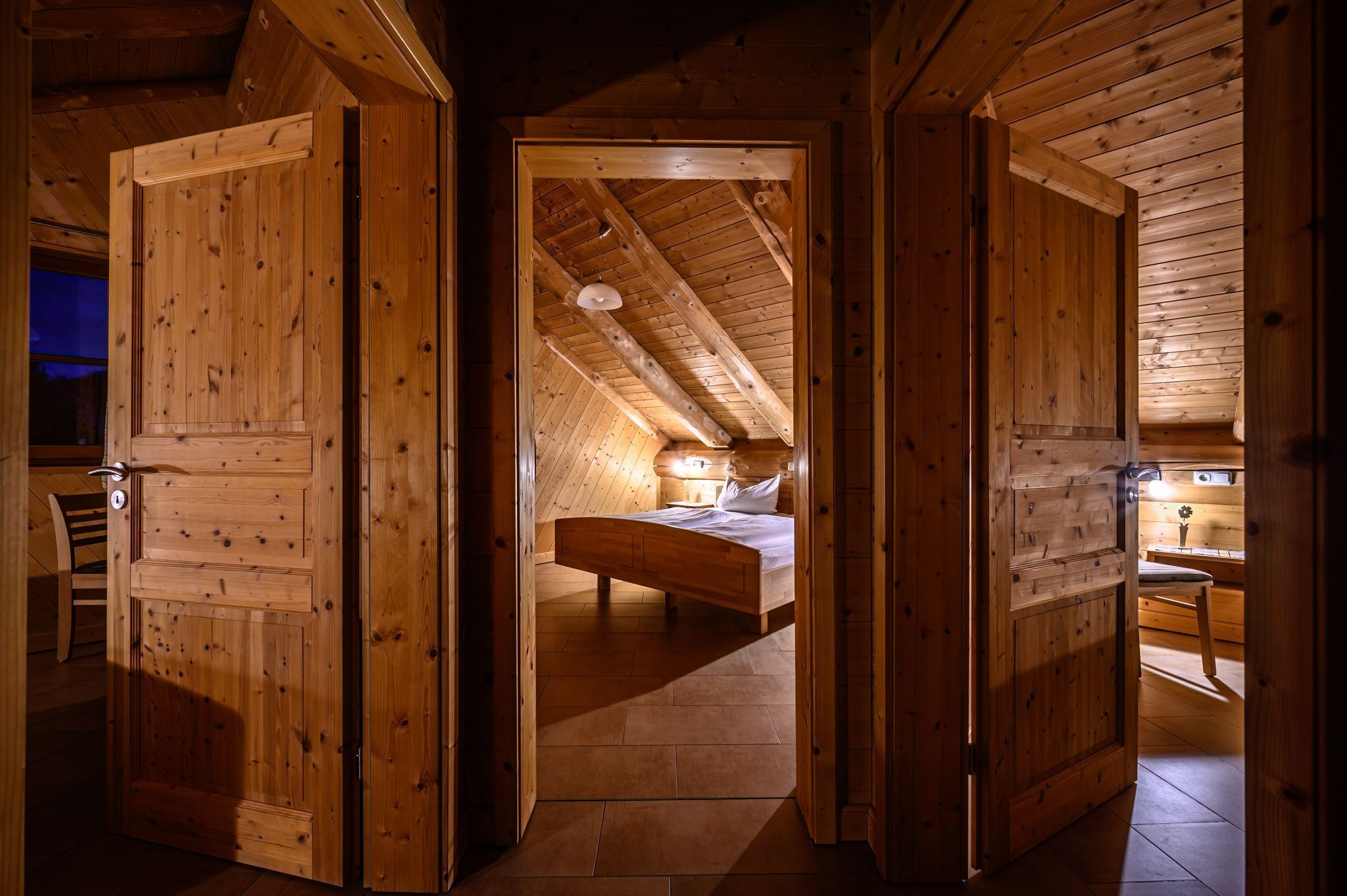 Un intérieur en bois avec un plafond en pente, un lit et un espace bureau.