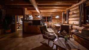 A log cabin interior with a dining area, kitchen, and seating space. - Natural log house Morgensonne - Heumann's log houses by the forest (Pottenstein)