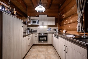 A modern kitchen with wooden cabinetry, stainless steel appliances, and a tiled floor.
