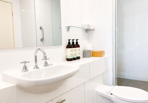 A modern bathroom with a white sink, a mirror, and a glass shower enclosure.