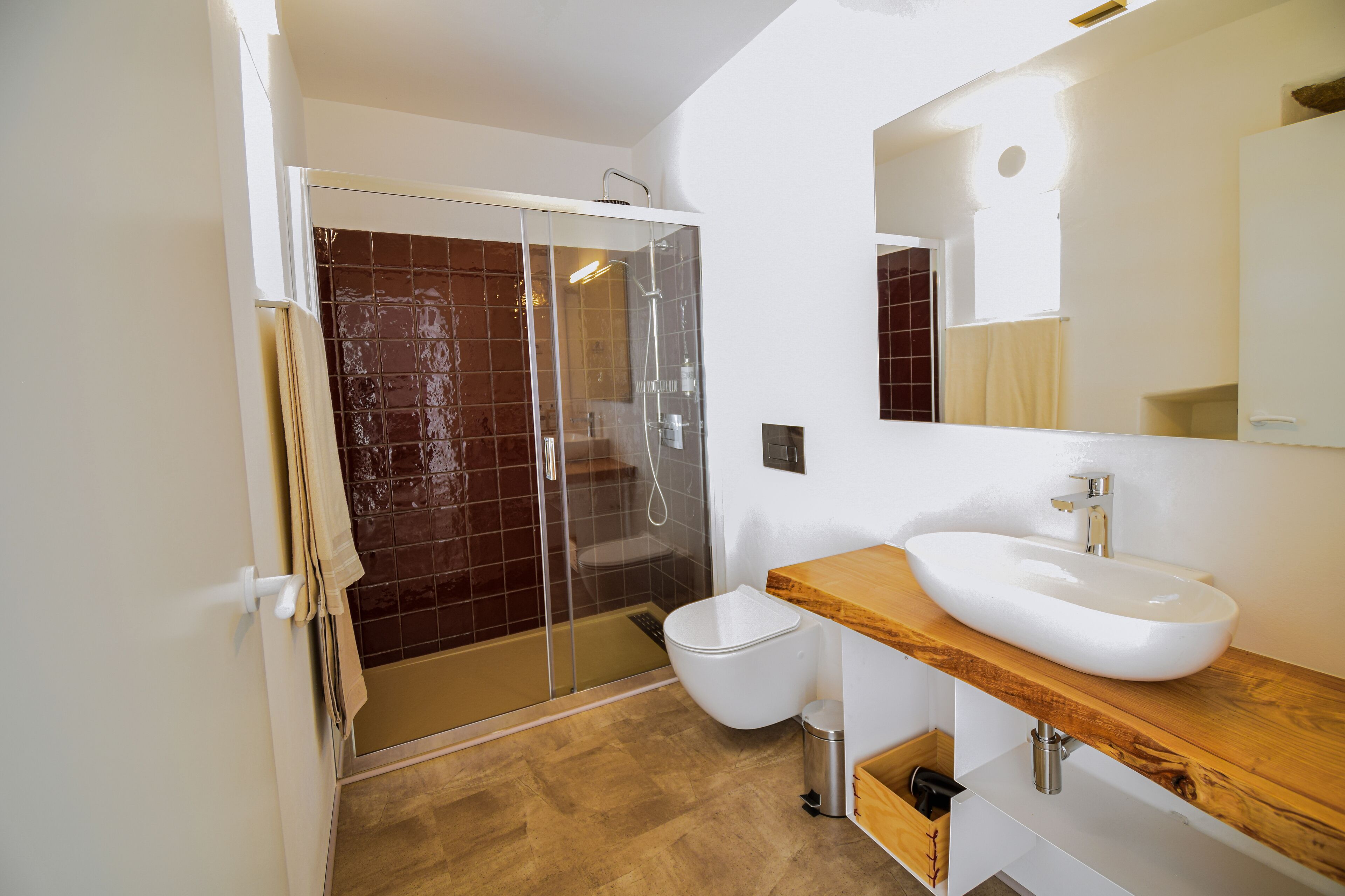 A modern bathroom with a glass-enclosed shower, a white toilet, and a wooden vanity with a sink.