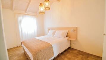 Un dormitorio con cabecera de madera, una cama grande con ropa blanca y dos lámparas colgantes.