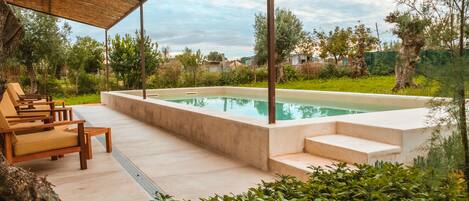 Una piscina al aire libre, sillones reclinables de piscina