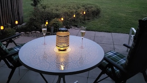 A round outdoor table with two chairs, a lit lantern, and two glasses of wine. - Apartment - Apartment Kreckel (Schliersee)