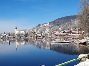 Un pueblo a orillas del lago con edificios tradicionales, una iglesia y un muelle.