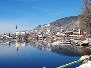 Ein Dorf am See mit traditioneller Bebauung, einer Kirche und einem Steg.