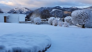 A snow-covered landscape with a building, trees, and mountains in the background. - Apartment - Apartment Kreckel (Schliersee)