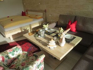 Un coin repas bien aménagé, avec une table dressée pour quatre personnes, un canapé et un lit en arrière-plan.