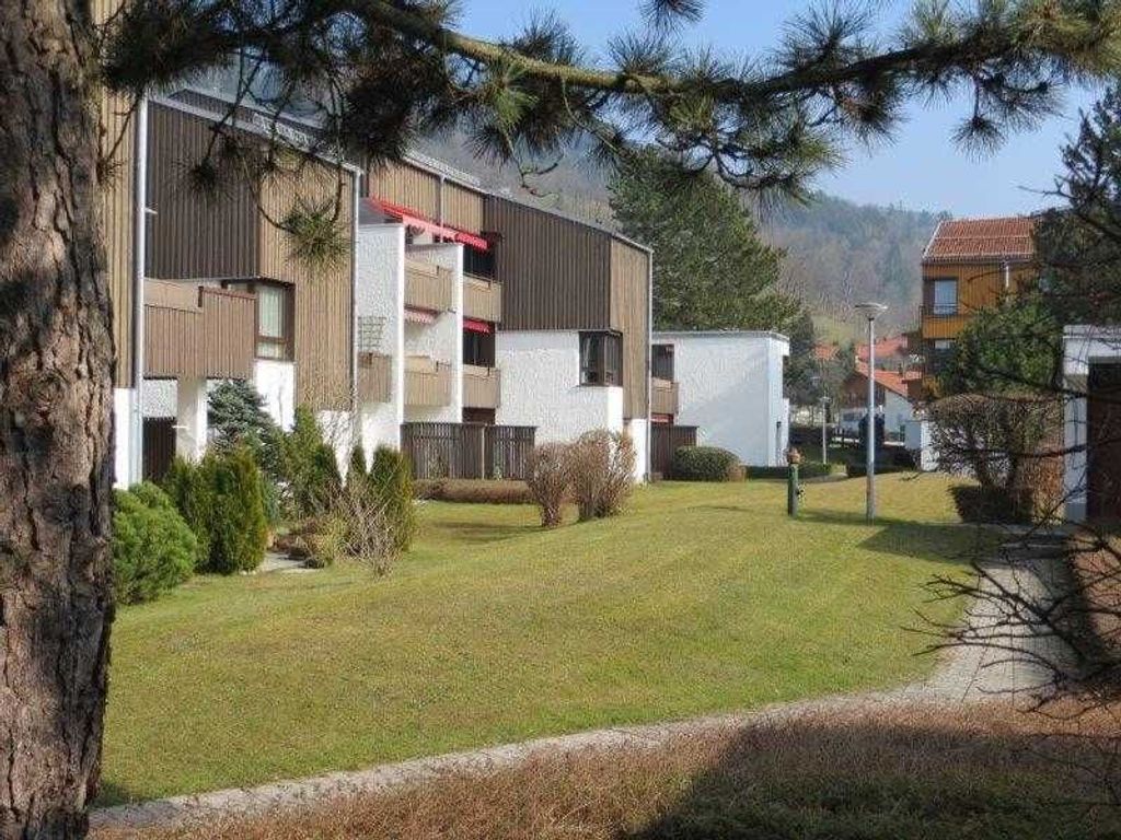A modern building with a flat roof, multiple balconies, and a well-maintained lawn.