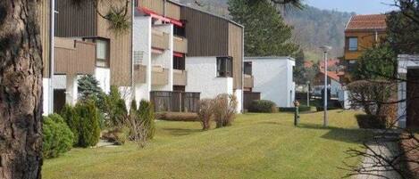 A modern building with a flat roof, multiple balconies, and a well-maintained lawn.