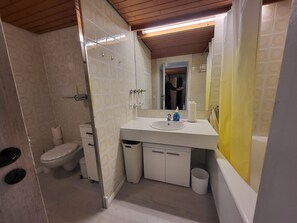 Un baño con inodoro, lavabo, espejo y zona de ducha.