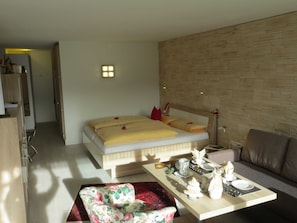 Une chambre moderne comprenant un lit, un canapé, une table à manger et un petit coin cuisine.