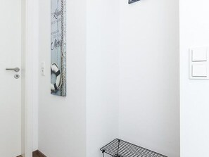 A white room with a door, a mirror, and a black metal shelf.