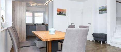 Un comedor moderno con una mesa de madera y cuatro sillas grises.
