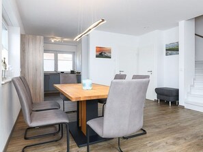 A modern dining area with a wooden table and four grey chairs.