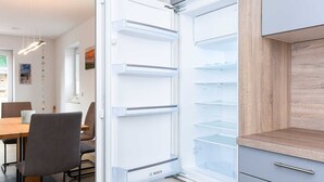 Eine moderne Küche mit einem eingebauten Kühlschrank, Holzschränken und einem Essbereich mit Tisch und Stühlen.