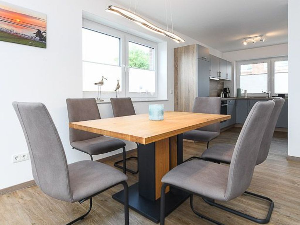 A modern dining area with a wooden table and grey upholstered chairs.