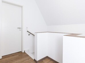 A white interior with a wooden floor, a white door, and a white wall with a corner. - Licht Vacation Cottage, Germany (Dornum)