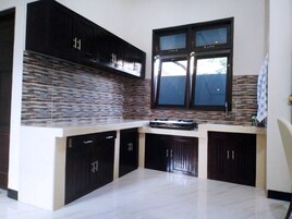 A modern kitchen with dark cabinets, a tiled backsplash, and a window above the sink.