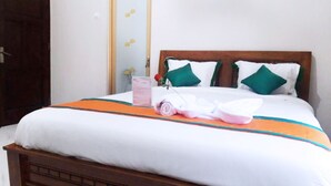 A neatly made bed with white bedding, green pillows, and an orange decorative border. - Homestay Purbalingga Tengah Kota by Simply Homy (Purbalingga)