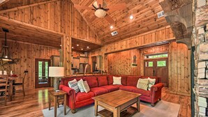 Un interior de madera con un sofá seccional rojo, una mesa de centro de madera, y un comedor con sillas y una mesa.
